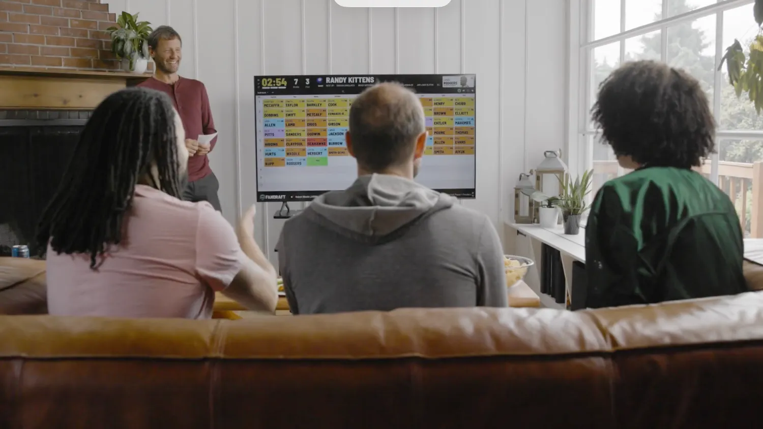 A fantasy football league reacting to a FanDraft pick announcement on the big screen